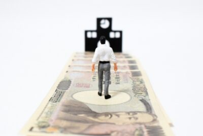 奨学金でお金で道を作り学校に行くイメージのスーツ姿男性